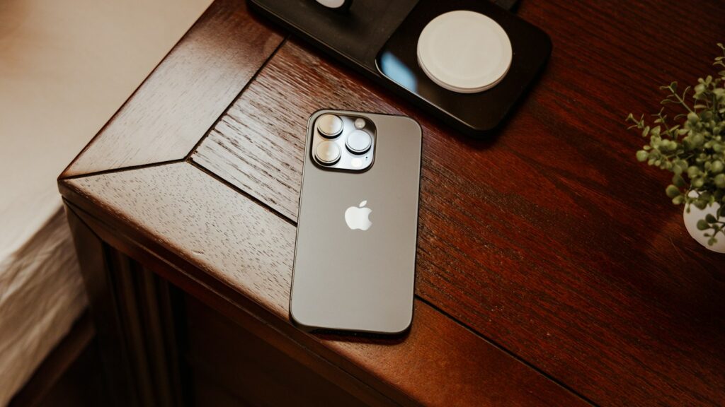 iPhone on a wooden desk beside a circular wireless charging puck